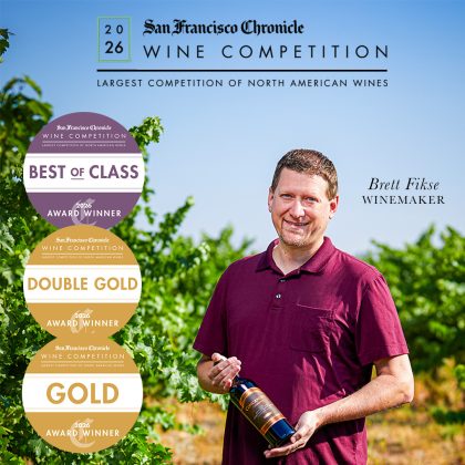 Winemaker Brett Fikse in the vineyard holding a bottle of Concannon wine